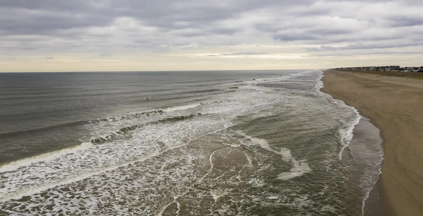 Aerial view of a grey winter day at Bay Head, New Jersey, with lines of swell breaking along an empty sand beach