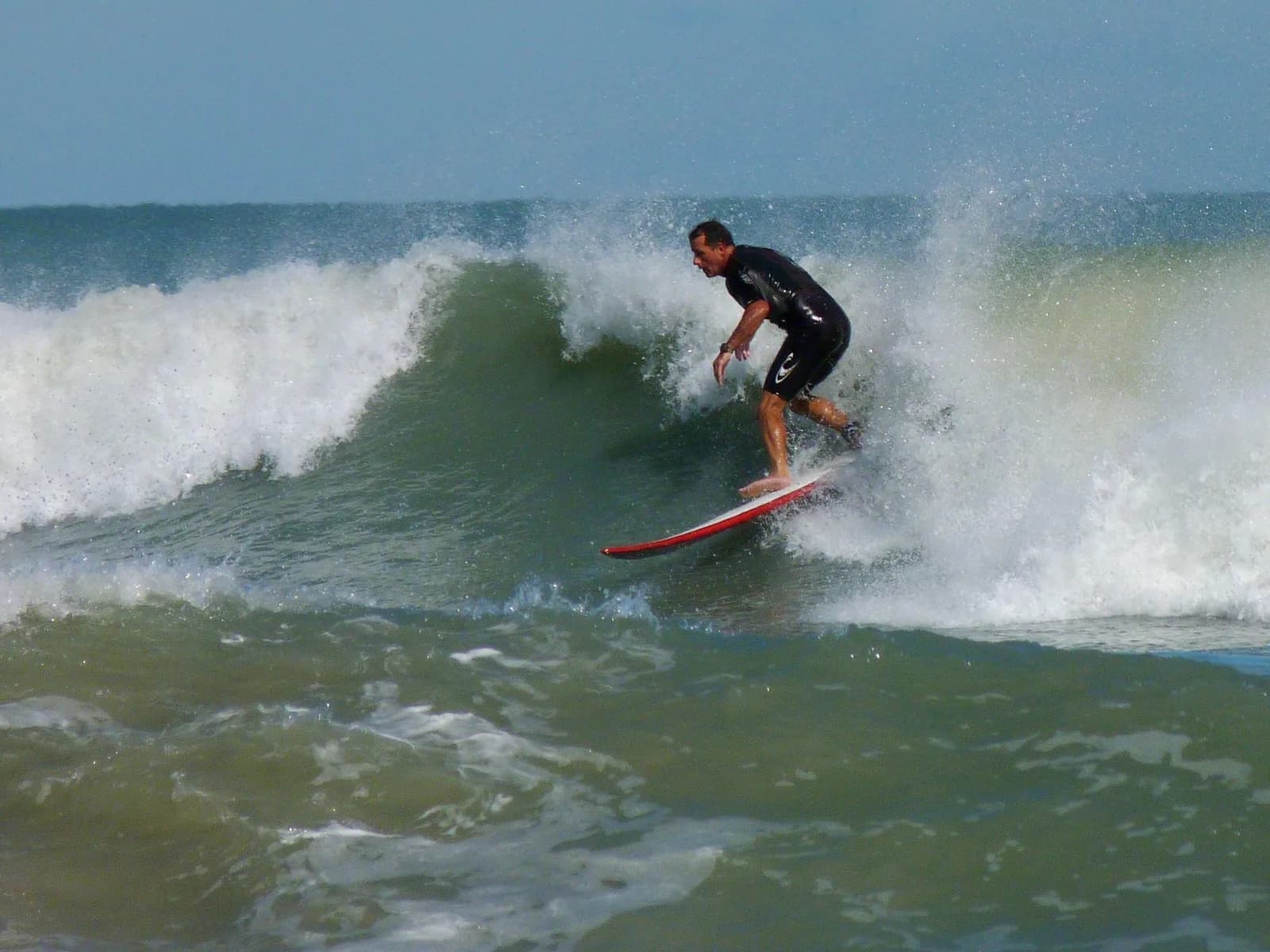 A surfer riding a breaking wave at Cocoa Beach, spray blowing back off the lip