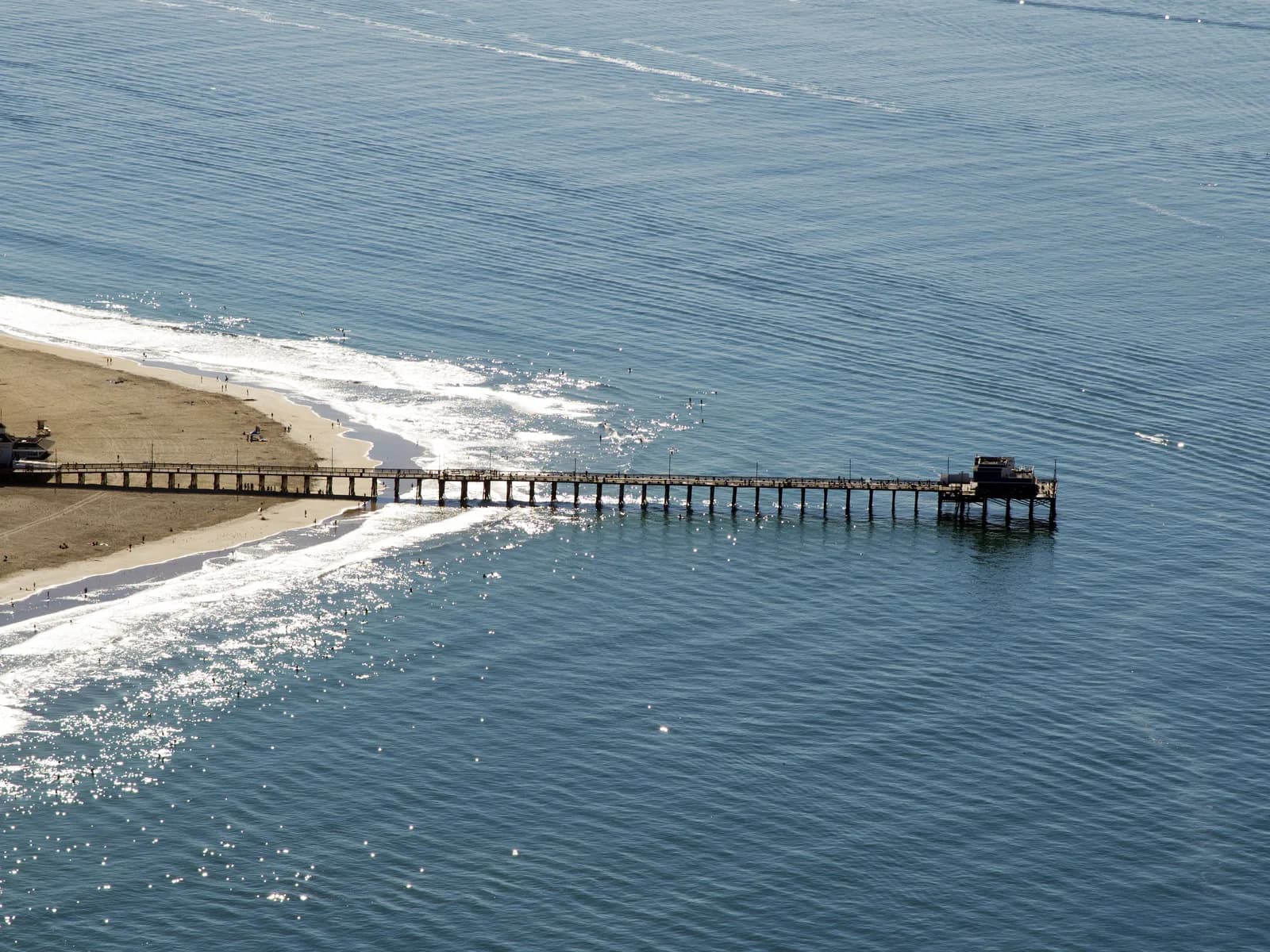 Aerial view of Newport Pier with whitewater on the sandbars on both sides of the pier